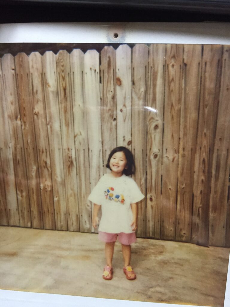 a girl standing in front of a wooden wall