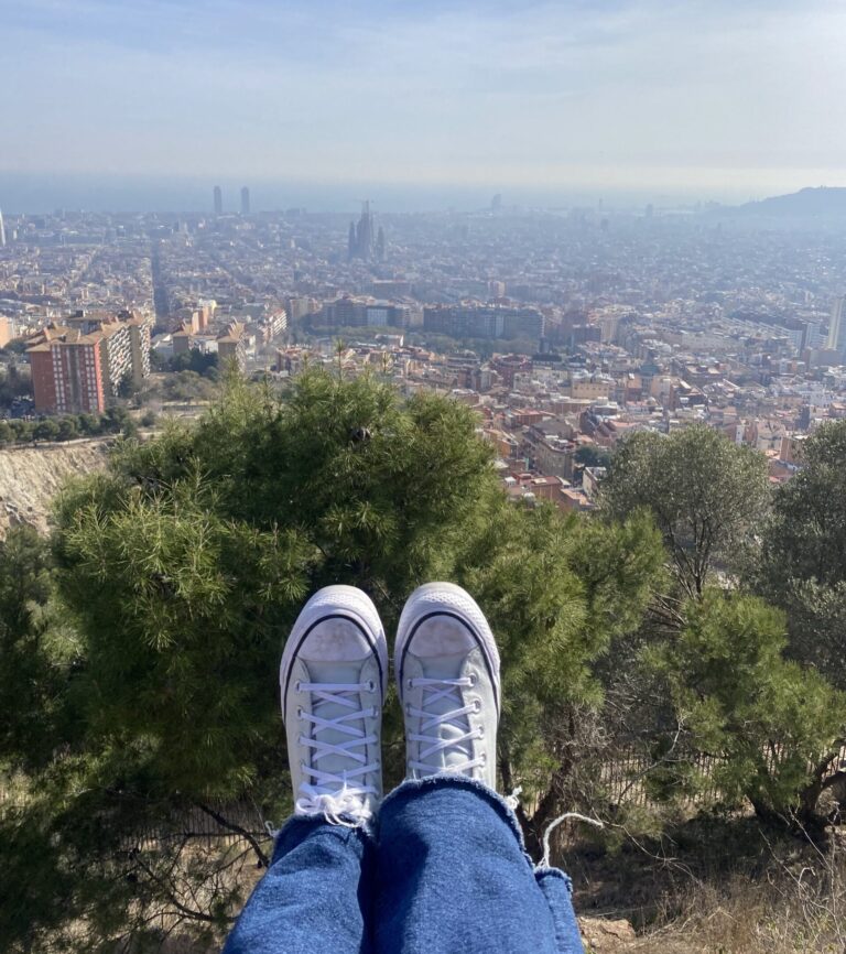 Barcelona city view with two legs and converse shoes in the background